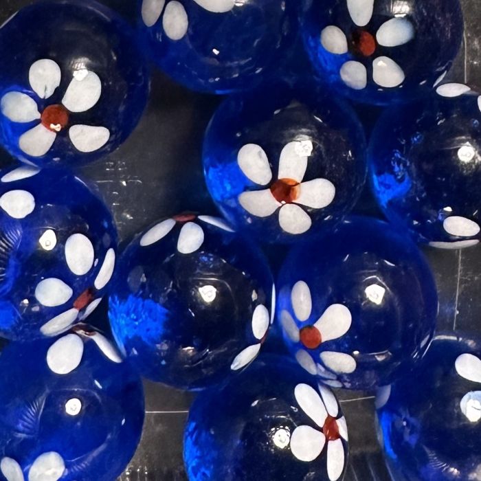 Frühling dunkelblau 16mm: handgefertigte Glasmurmel aus durchscheinend dunkelblauem Glas mit weißen Blümchen mit rotem Herz